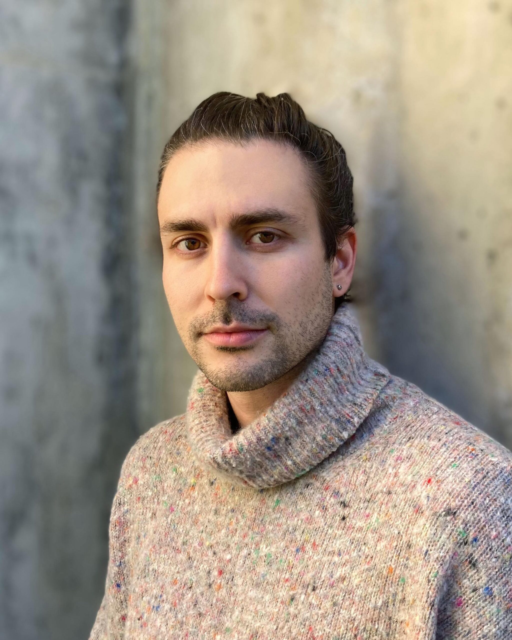 Peter Vale in flecked turtleneck sweater in front of a concrete wall